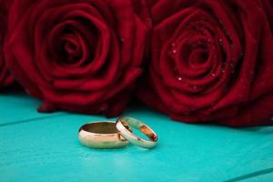 anillos de boda y rosas rojas. ramo de novia sobre fondo de madera azul. enfoque selectivo. copia espacio y maqueta