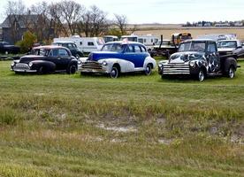 a row of classic vehicles in a field photo