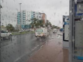 lluvia en los emiratos árabes unidos hermosa vista del lado de la carretera y sala de estar repartidor disfrutando en la lluvia bebé jugando silla hierba en la lluvia, el tráfico continúa en la carretera en un día lluvioso foto