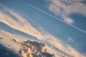 Pre-stormy sky at sunset streaked with condensation stripes from aircraft, beautiful nature, environmental and economic problems photo