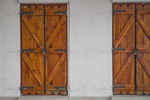 puertas de persianas de madera en una antigua pared blanca, idea para un fondo o papel tapiz, concepto de uso y conservación de ciudades antiguas, publicidad o artículo sobre viajes y turismo foto