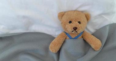 A sad teddy bear lies sick in bed with disappointment and discouragement photo