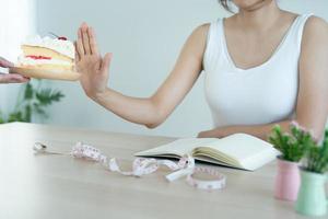 Hands sends plate of cake to slim women. The woman pushed the plate the cake and refused to eat sweets and fat. people Health Care and diet concept photo