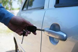 The car owner uses the key to open the car door. photo