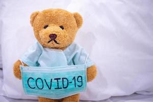 Sick teddy bear with mask writes Covid-19. The situation of the 2019-nCoV virus infection in Wuhan is spreading around the world. Deadly plague of the world. concept wear mask to protect coronavirus photo