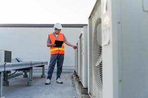 Factory engineers walking and checking the cooling system of the factory. Fore man records the condition of the compressor before maintenance according maintenance plan. photo