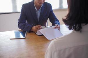 Executives are interviewing candidates and holding a tablet, opening the resume from the email that the applicant submits online. Discussing attitudes about work and special abilities. Considerations photo