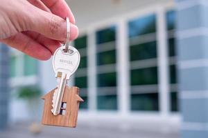 la mano del hombre que entrega la llave de la casa es una oferta para vender la casa. el concepto de vender una casa en alquiler-compra. foto