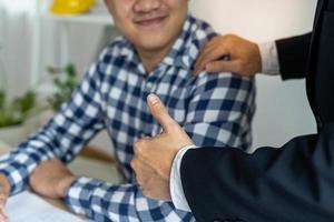 el jefe levantó el pulgar hacia un colega mientras daba consejos y apreciaba el trabajo. empleado masculino sonrió alegremente después de recibir elogios de sus colegas foto