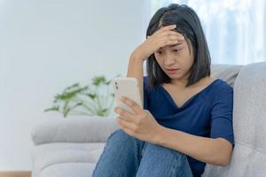 Beautiful Asian woman disappointed and sad after receiving bad news over the phone. Stressed girl confused with unhappy problems in life, arguing with her boyfriend. photo