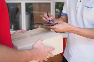 The sender holds the box, prepares to send the order and sign the recipient on the smartphone. photo