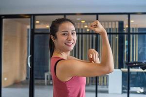 la chica del gimnasio estira los músculos, muestra fuerza, buena salud y sonríe en el gimnasio. ejercitar conceptos saludables foto