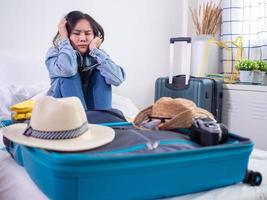 la mujer está estresada por prepararse para viajar. no hay suficiente ropa almacenada en la bolsa. preocuparse por viajar foto