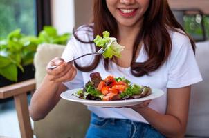 las mujeres jóvenes que tienen la intención de perder peso están comiendo una ensalada de verduras de salmón para una buena salud. mujeres que eligen el concepto de dieta de alimentos saludables foto