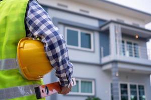 el inspector masculino estaba vigilando la casa supervisada, portando equipo y un casco, usando un chaleco en el desarrollo de conceptos de vivienda e inmobiliarios. foto