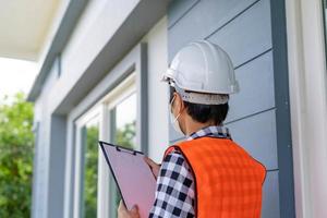 An inspector or engineer is inspecting and inspecting a building or house using a checklist. Engineers and architects work to build the house before handing it over to the homeowner. photo