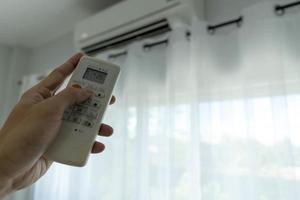 Man's hand off the air conditioner by holding the remote control to the cooler system after no one is in the room. save electricity,save  energy and protect the environment.