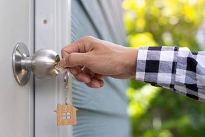 The new homeowner uses the key to open the door. Selling and renting a concept house. photo