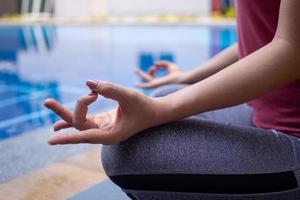 Asian women wearing athletic clothing, yoga, twisting pose, swimming pool side relaxed healthy exercise concepts. photo