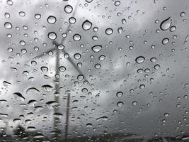 Rain on the car glass Outside is a windmill view. Sad and lonely background photo