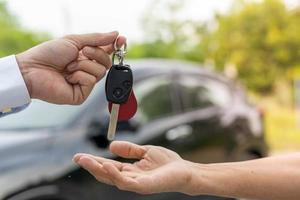 selling car, car sale, deal concept The dealer gives the car keys to the new owner or renter with an insurance contract. photo