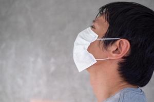 imagen facial de hombres asiáticos que usan máscaras para protegerse contra el virus corona o covid 19 y humos y polvo tóxicos. p. m. 2,5 foto