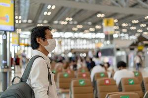 Asian men wear masks while traveling in high-risk areas to reduce the spread of coronavirus. Tourists wait to board planes during the COVID-19 pandemic. photo