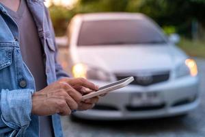 seguridad de emergencia. el hombre usa el teléfono para llamar a un mecánico porque su auto se descompone. seguro de coche y seguro de accidentes durante el viaje foto