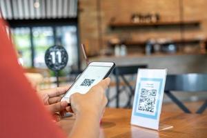 las manos de las mujeres están usando el teléfono para escanear el código qr para seleccionar el menú de comida. Escanea para obtener descuentos o pagar la comida. el concepto de usar un teléfono para transferir dinero o pagar dinero en línea sin efectivo. foto