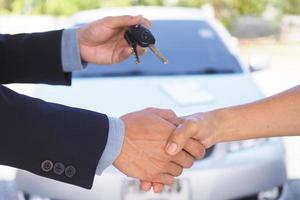 los vendedores de autos dan la mano a los inquilinos. y enviar las llaves al nuevo propietario foto