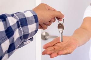 Homeowner or sales representative giving the keys to the hand of the tenant. photo