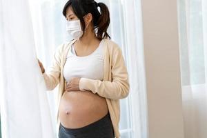 The woman is 28 weeks pregnant, wearing a face mask to prevent viruses and pollen or pm2.5 dust. photo