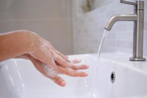 Wash your hands with soap, prevent virus and bacteria in the tap with running water. Good hygiene before eating or handling public items photo