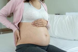 una mujer embarazada tiene dolor de espalda después de despertarse por la mañana. las mujeres embarazadas están cerca de dar a luz foto