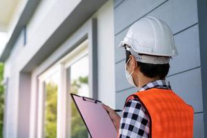 un inspector o ingeniero está inspeccionando e inspeccionando un edificio o una casa usando una lista de verificación. ingenieros y arquitectos trabajan para construir la casa antes de entregársela al propietario. foto