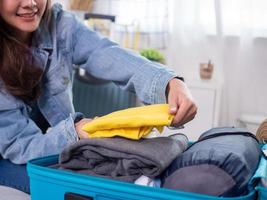 las mujeres jóvenes que guardan ropa en el equipaje se preparan para un viaje de vacaciones. concepto de viajes y vacaciones. día feliz foto