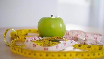 cinta métrica alrededor de la manzana verde. comer para una buena salud y pérdida de peso. concepto de dieta foto