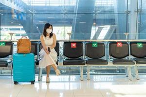 Asian women wear a mask and sit between chairs to reduce the spread of the coronavirus. Tourists wait to get on planes during the covid-19 outbreak. photo