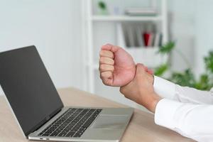 Businesswoman hurts wrist while working. A woman uses a computer for a long time causing Trigger Finger. Office Syndrome Concept.