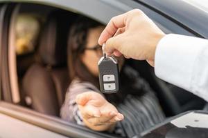 un empleado de una empresa de alquiler de coches turísticos presenta las llaves del coche con una prueba de conducción. buen servicio antes de acordar un contrato de arrendamiento o compra.