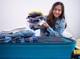 las mujeres o los turistas están empacando ropa en bolsas para las largas vacaciones o vacaciones. prepárate para viajar foto