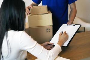 la chica compradora firma en el portapapeles para recibir la caja del paquete del repartidor. servicio de entrega rápida foto