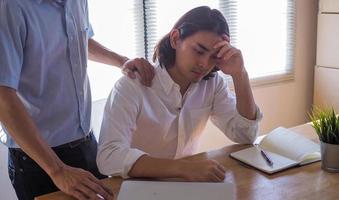 un hombre de negocios para apoyar y alentar a un colega que está trabajando mal hasta que lo despidan foto