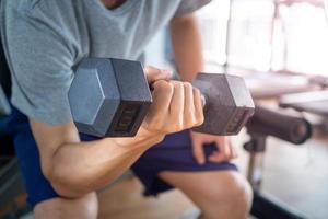 primer plano del brazo del hombre con mancuernas haciendo ejercicio en el gimnasio. concepto de mantenimiento de la salud foto