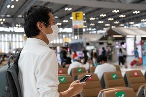 Asian men wear masks while traveling in high-risk areas to reduce the spread of coronavirus. Tourists wait to board planes during the COVID-19 pandemic. photo