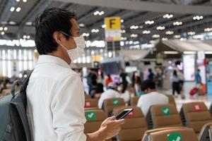 Asian men wear masks while traveling in high-risk areas to reduce the spread of coronavirus. Tourists wait to board planes during the COVID-19 pandemic. photo