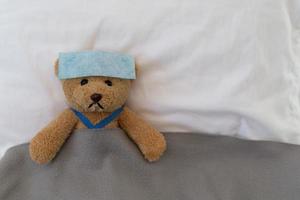 un oso de peluche triste yace enfermo en la cama con decepción y desánimo foto