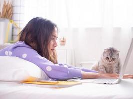 una hermosa mujer sonrió y jugó con gatos en la cama de la casa. foto