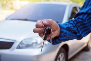 The car owner is standing the car keys to the buyer. Used car sales photo