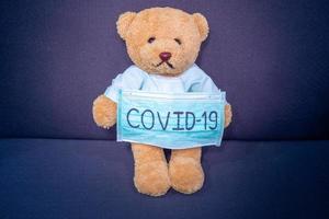 oso de peluche enfermo con máscara escribe covid-19. la situación de la infección por el virus 2019-ncov en wuhan se está extendiendo por todo el mundo. plaga mortal del mundo. concepto usar máscara para proteger el coronavirus foto